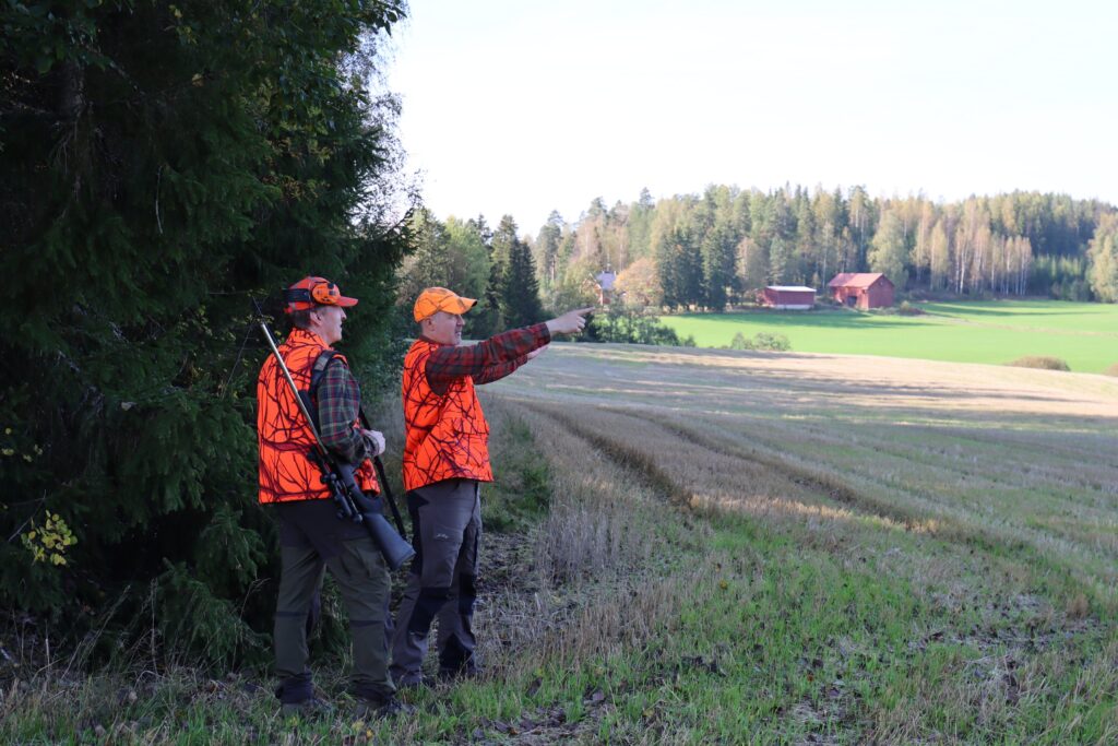 Metsästyksenjohtaja osoittaa toiselle passipaikan sijaintia.