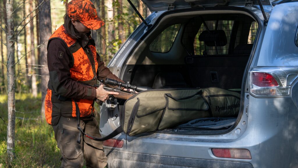 Metsästäjä laittaa kivääriä autoon.